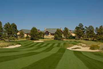 A view of the clubhouse with green protected by bunkers in foreground at Colorado Golf Club